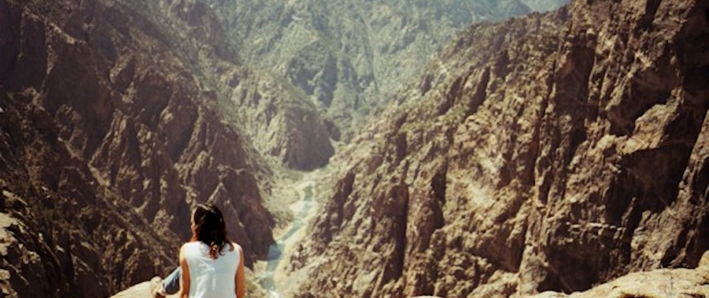 woman sits looking at sheer rock faces of black canyon