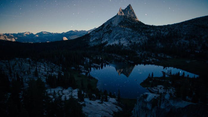 peak in yosemite california reflecting in mountain pond with stars visible