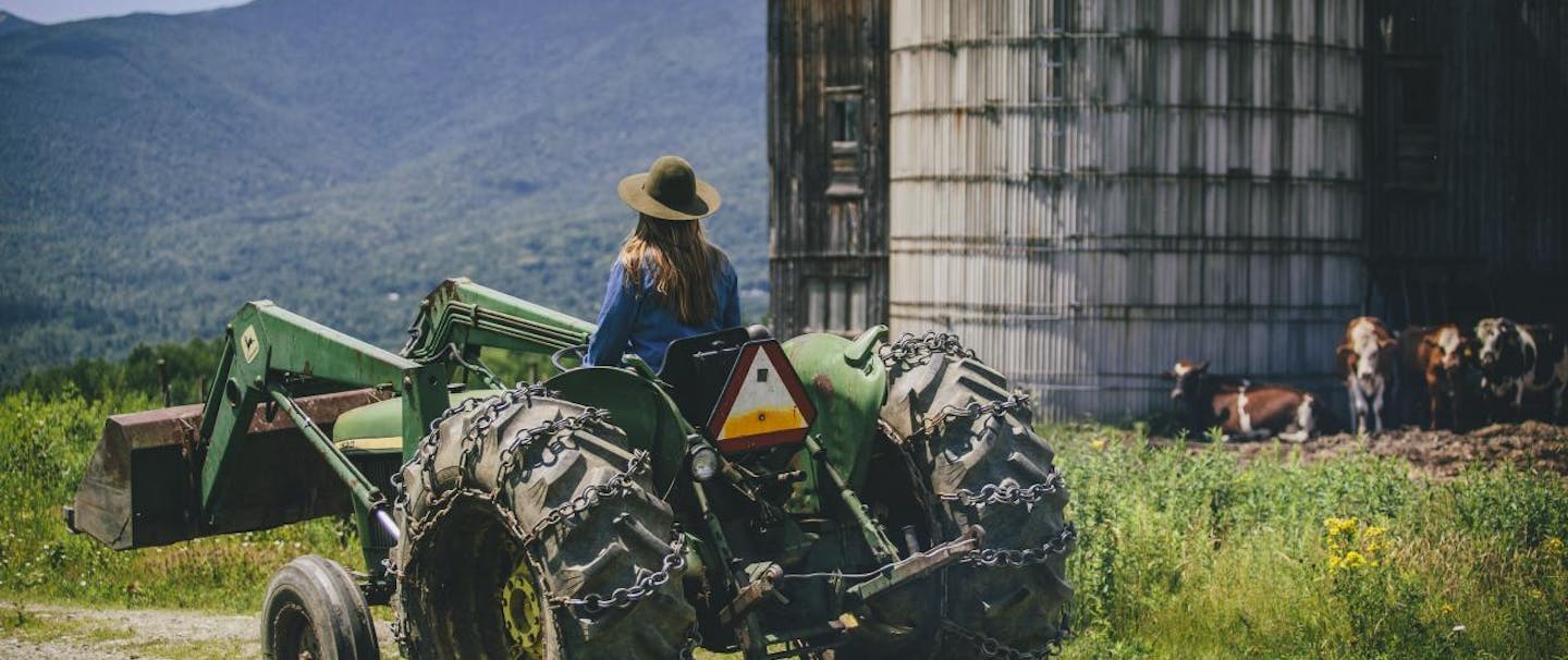 Marisa on a tractor with silo and mountains in background