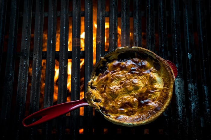finished dish in cast iron skillet on glowing grill grates