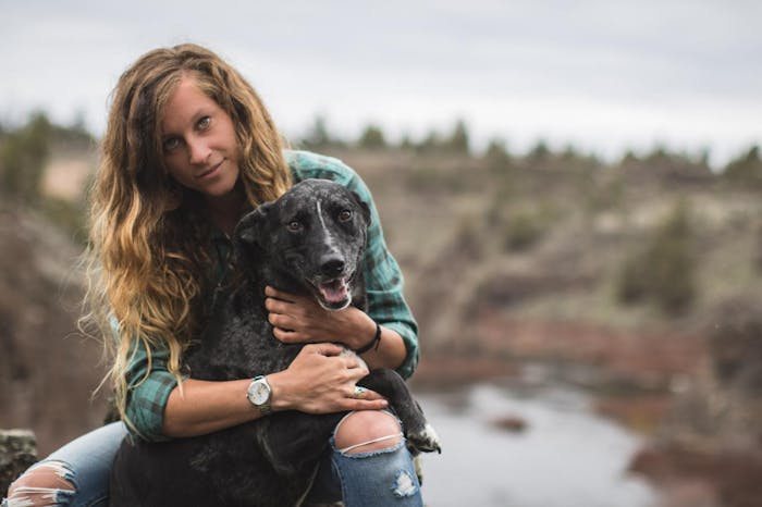 woman in green plaid shirt holds black dog