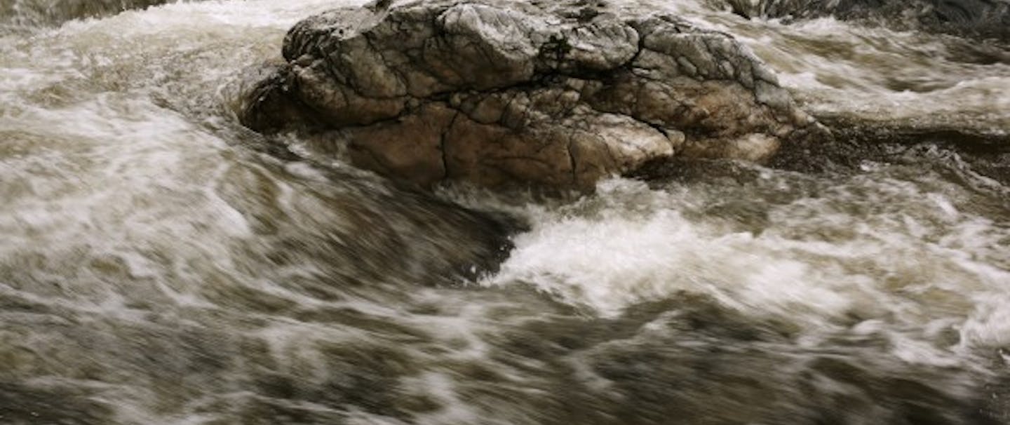 rushing river water with large central rock