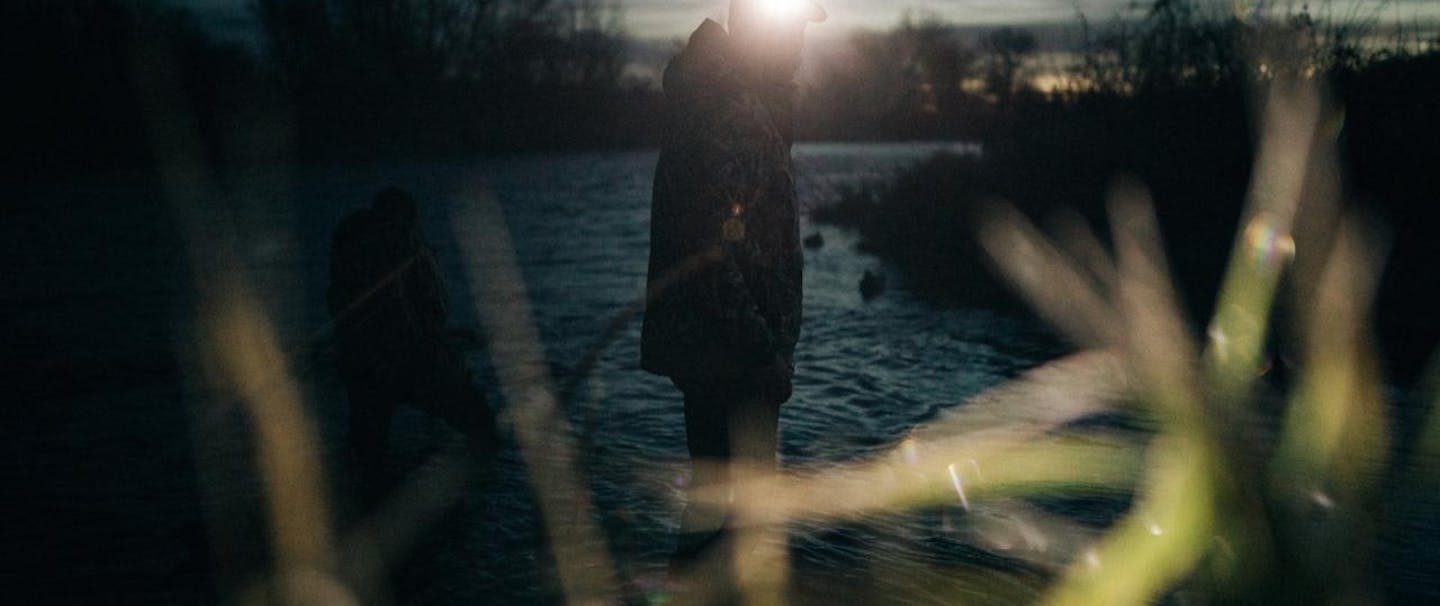 travis gillett in idaho silhouetted duck hunter stands in river at sunrise