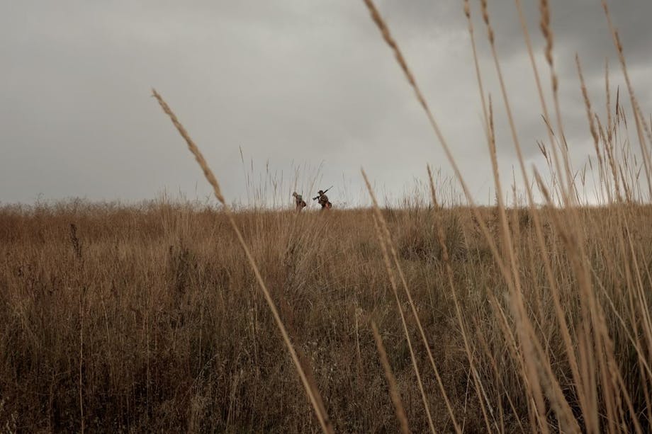 Greg-Reynolds hunters walk along ridge-line under overcast skies