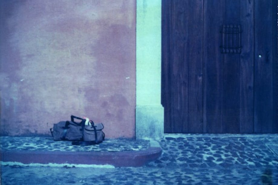 George Barnett; filson bags on black cobbles in front of wooden door