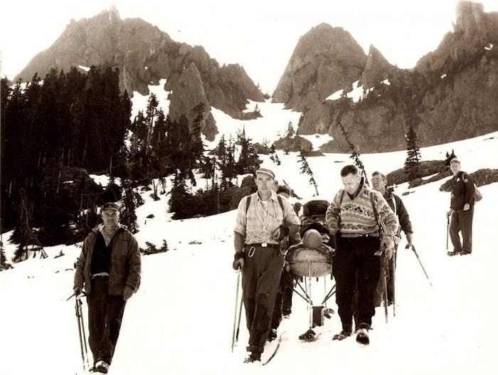 archival photo of seattle mountain rescue descending a mountain carrying an injured person