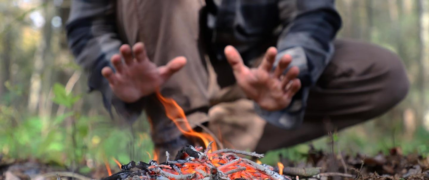 person warming hands behind burning kindling