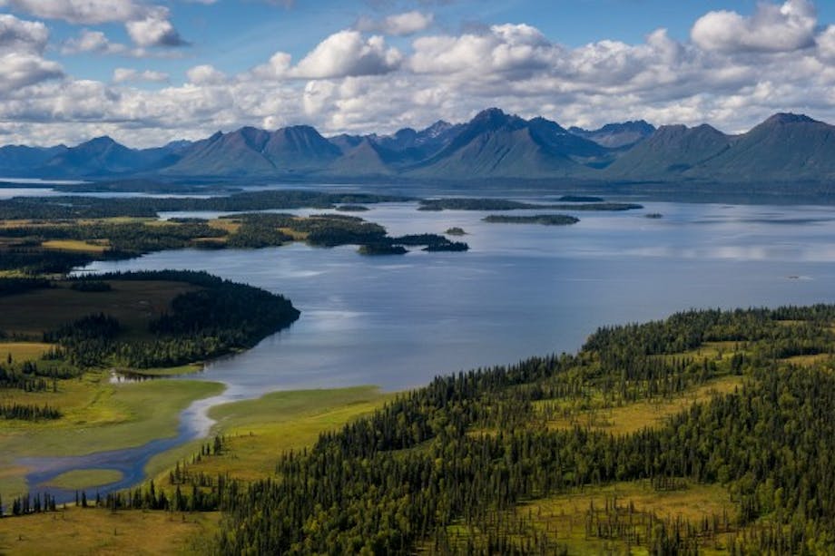 Jim Klug - Alaskan vista with large mountains in background and river opening up to large lake
