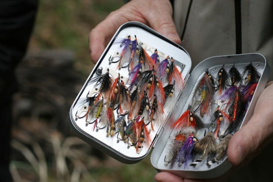 Hands hold Flybox full of fly fishing flies by Judith O'Keefe