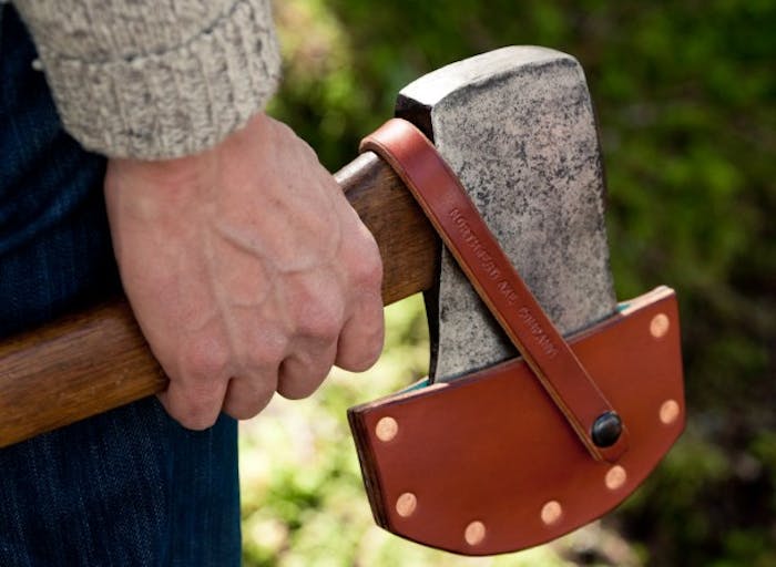 hand holds axe with leather axe blade cover