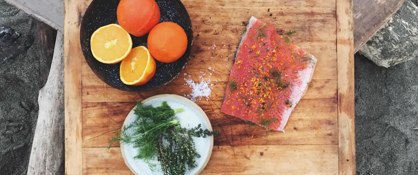 salmon filet with herbs and citrus and salt on cutting board