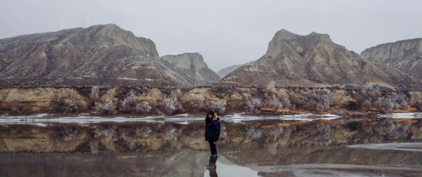 Tyson Edwards; Standing on a reflective body of shallow water with rocky mountains