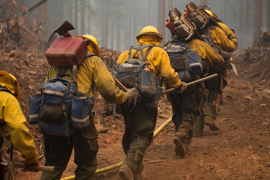 hotshots walking through dirt path in forest carrying their gear to location