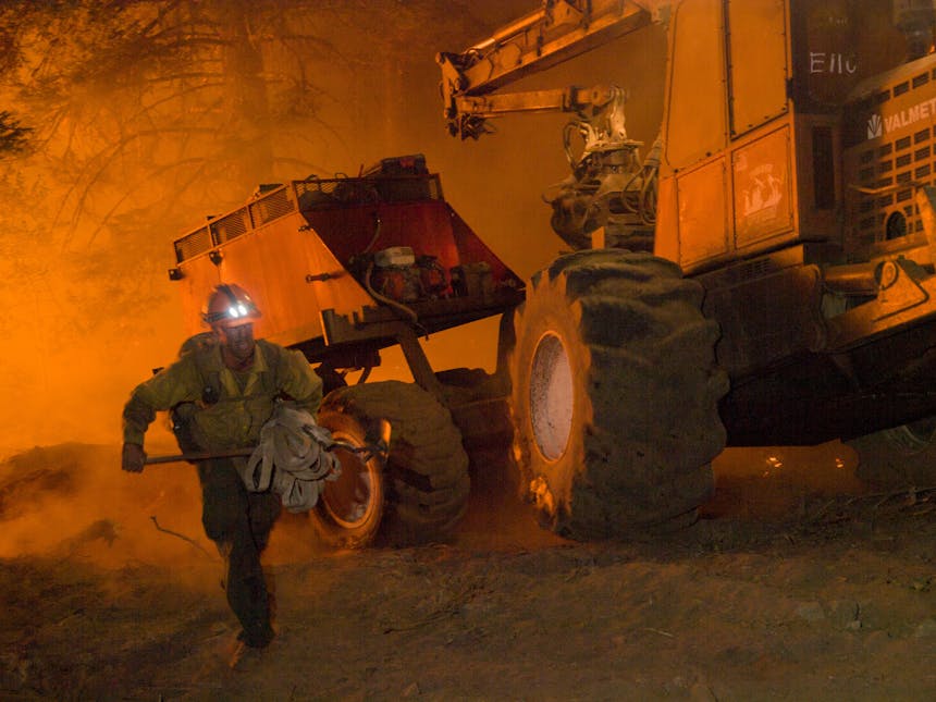 firefighter running to work with glow from fire reflected on equipment