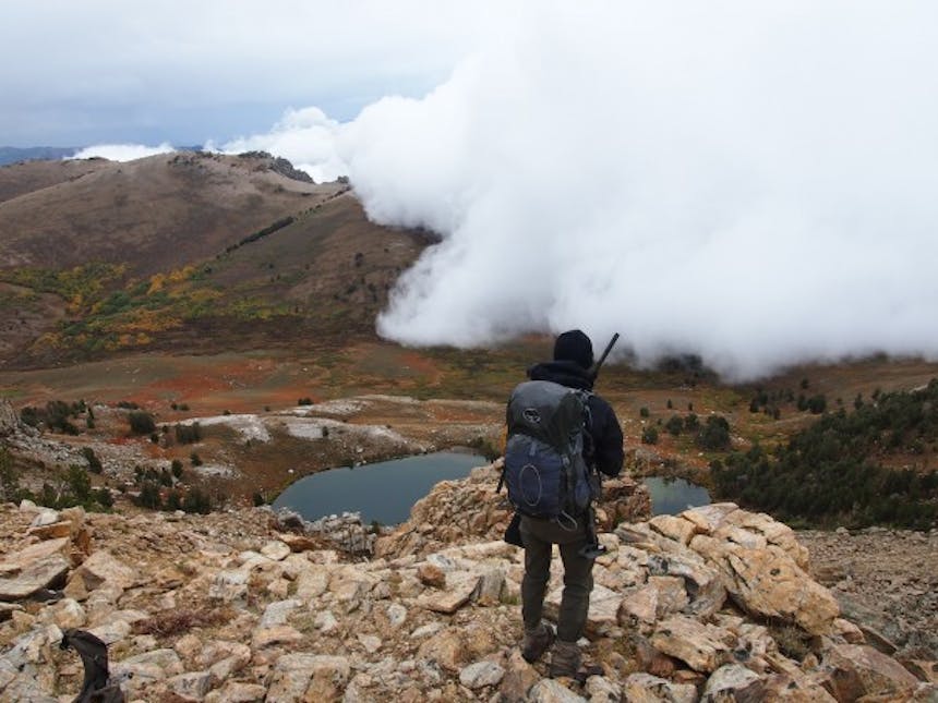 man standing on ridge looking down to pond