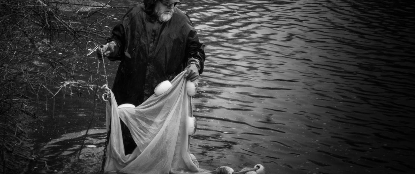 man moving fishing net in river
