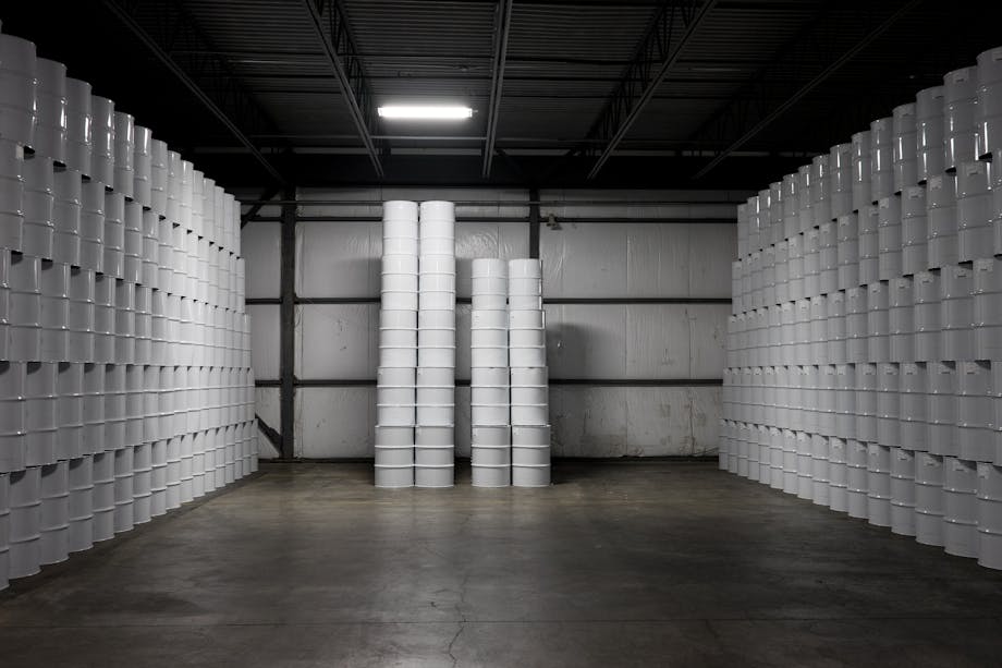 warehouse of white maple syrup barrels stacked to the ceiling on the right and left