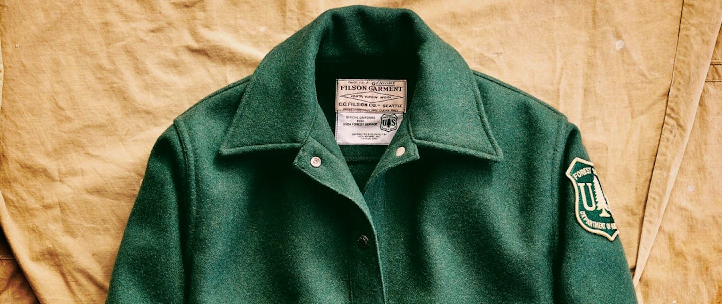 vintage green United States Forest Service and Filson jacket with department patch on brown canvas backdrop