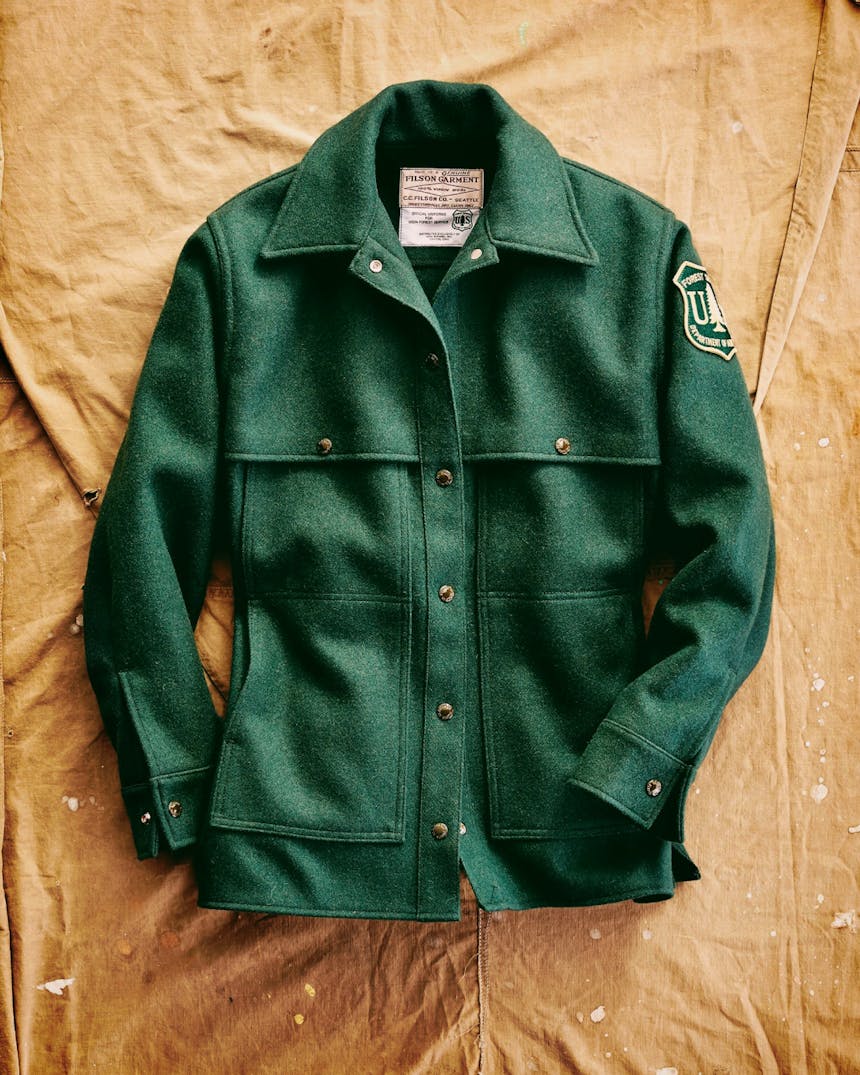 vintage green United States Forest Service and Filson jacket with department patch on brown canvas backdrop