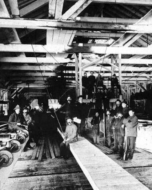 man sitting in saw mill for group photo