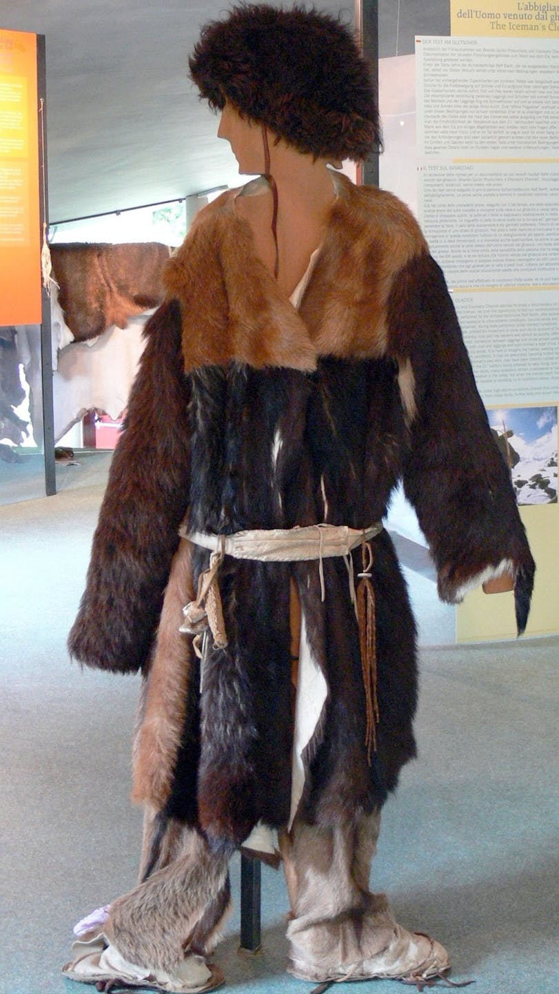 a museum reconstruction of an indigenous man wearing animal skins and furs of various brown colors