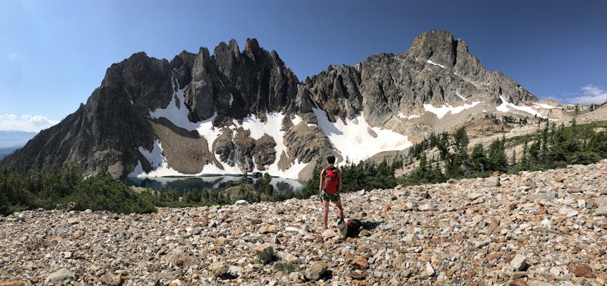 a landscape shot of jagged mountain peaks in the background of a girl standing on rocks for the photo