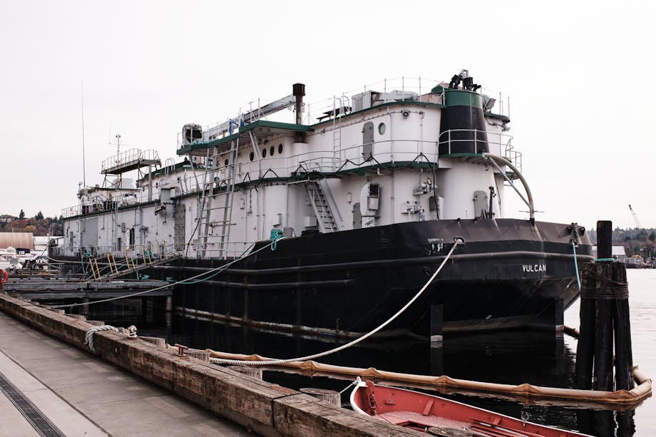 a dock view of a black hull and white maritime academy boat