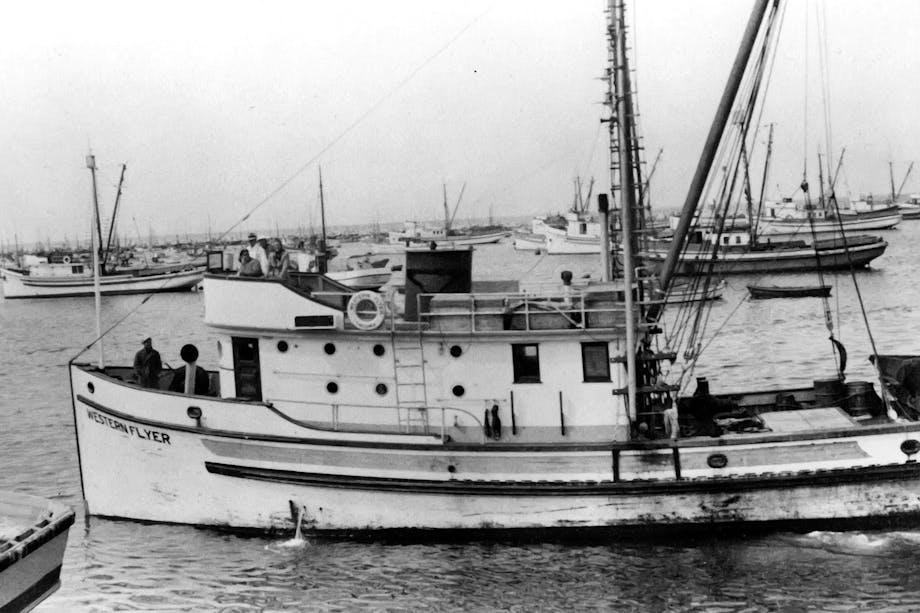 black and white image of boats anchored in a harbor. Small double deck fishing vessel named 