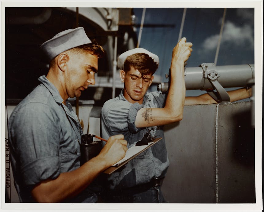 two seamen one standing at a large telescope and one taking notes on a clipboard