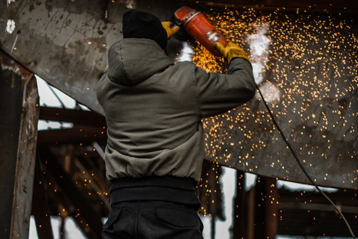 man using angle grinder on a steel portion of ship