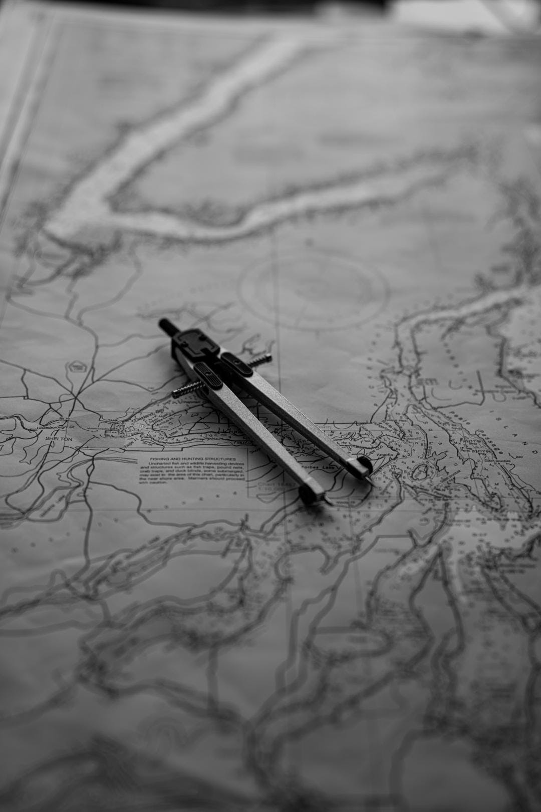 a black and white top down view of a nautical chart with a compass laying on top