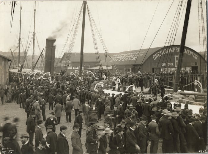 vintage black and white image of large crowd of people all in suits at the oregon improvement co. facility