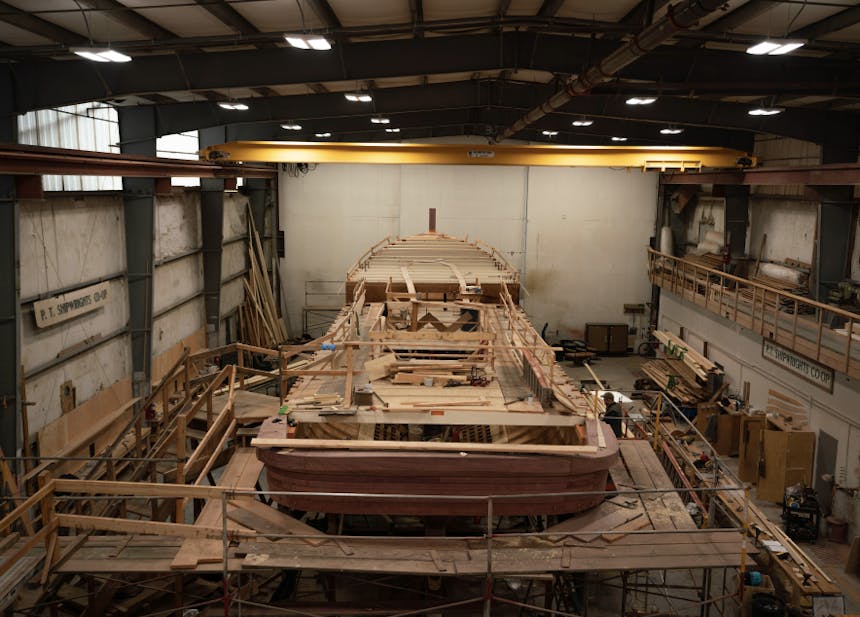 large wooden boat being built at a dry dock workshop facility