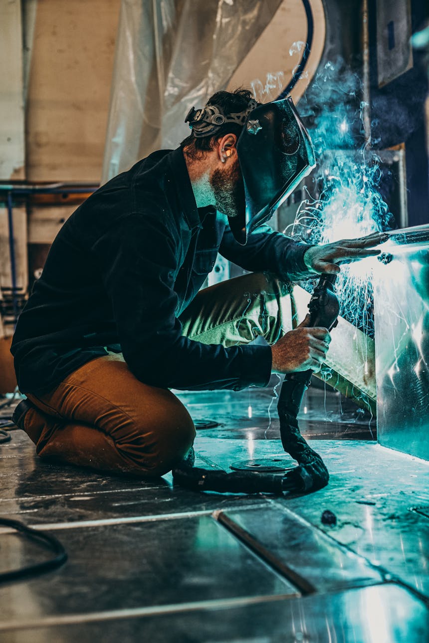 person wearing welding mask performs welding operations in a shop