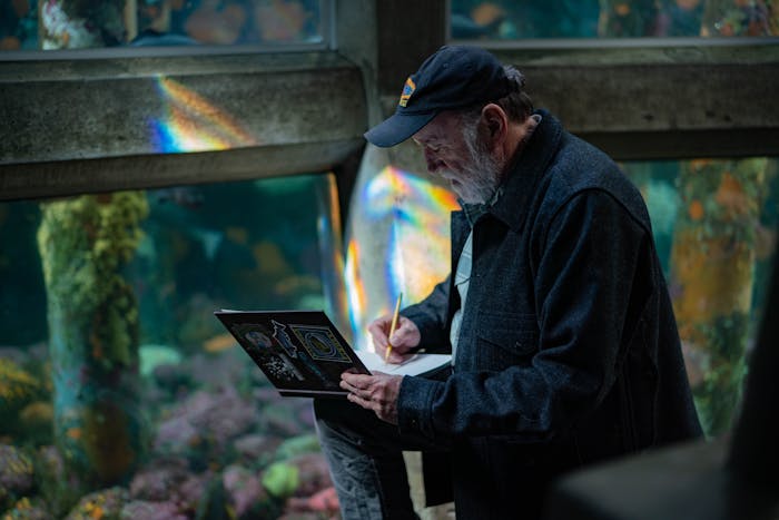 Man draws in a sketchbook at an aquarium