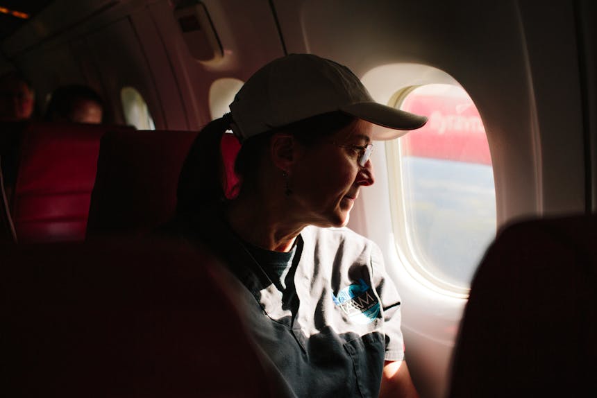 Kathy Burek sitting in window seat of airplane looking out the window