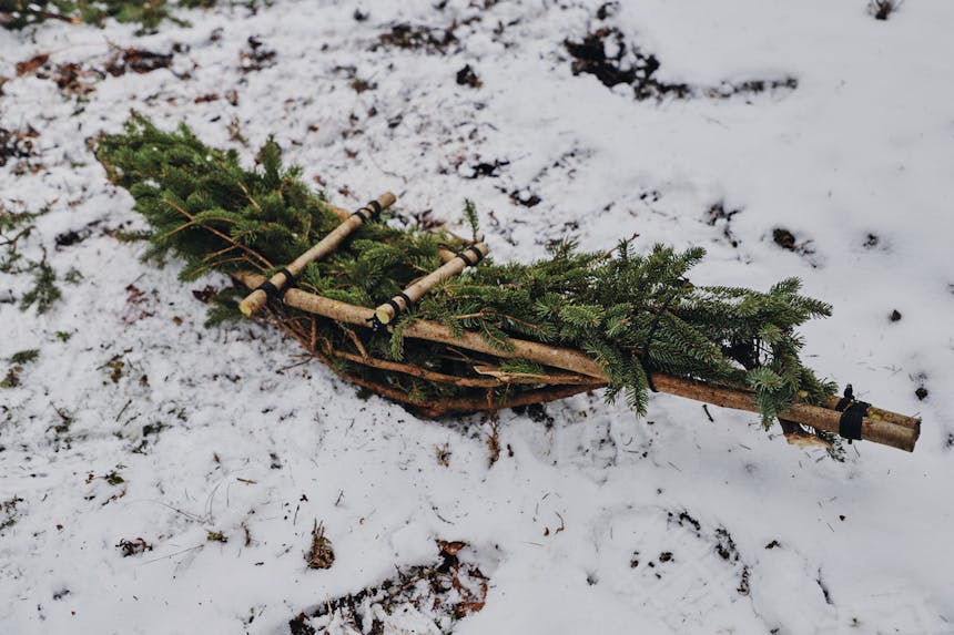 hand made snowshoe made of branches and pine needles laid on snowy ground