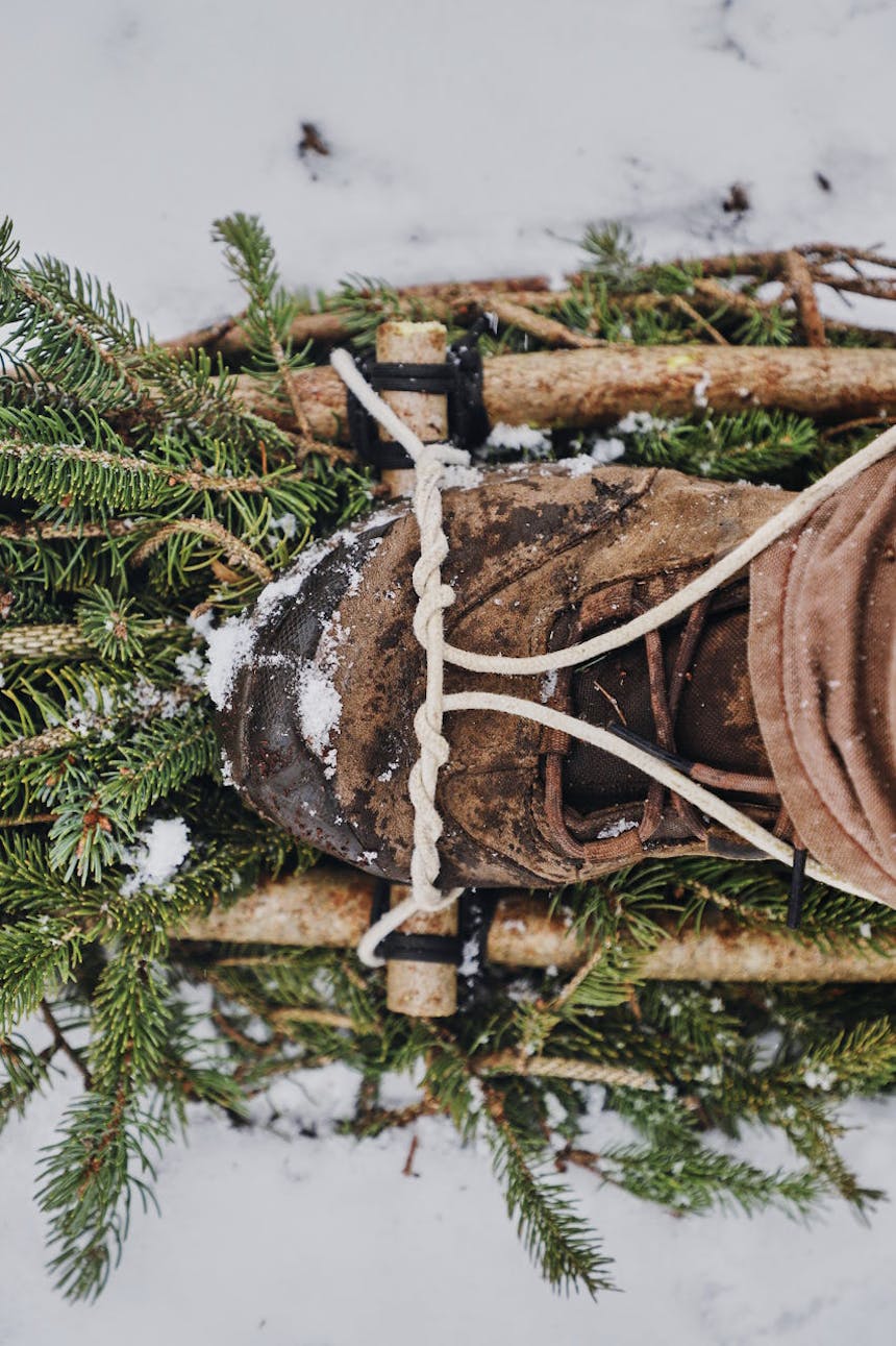 boot in improvised snowshoe made out of lashed pine boughs
