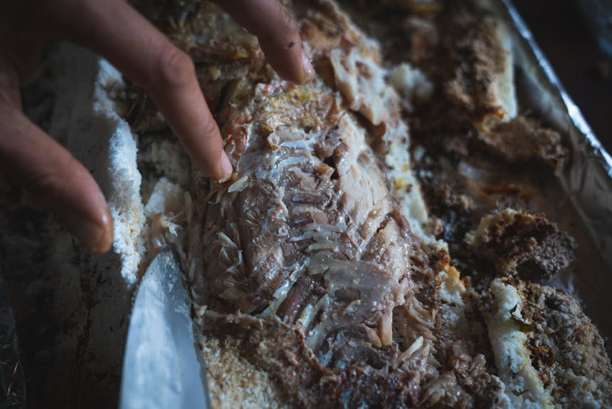 hand removing salt crust from a fish