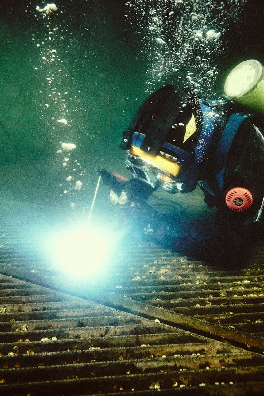 person in scuba gear performing underwater welding operations on metal sheet