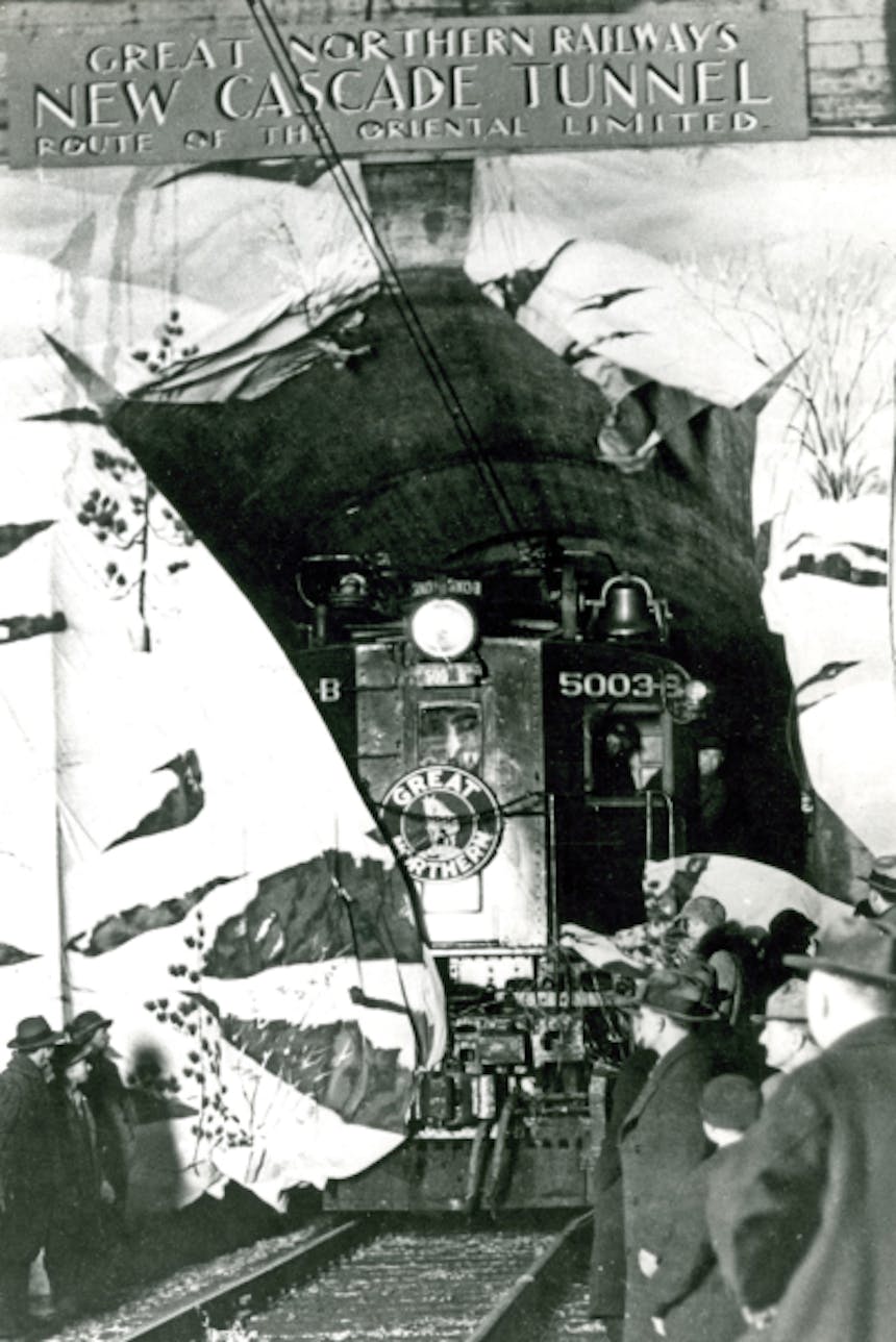 black and white image of people standing by rails watching the