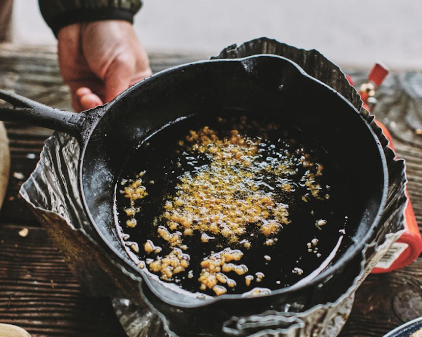 garlic toasting in oil on a small cast iron pan