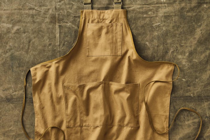 top down image of tan shop apron on top of a cloth covered surface