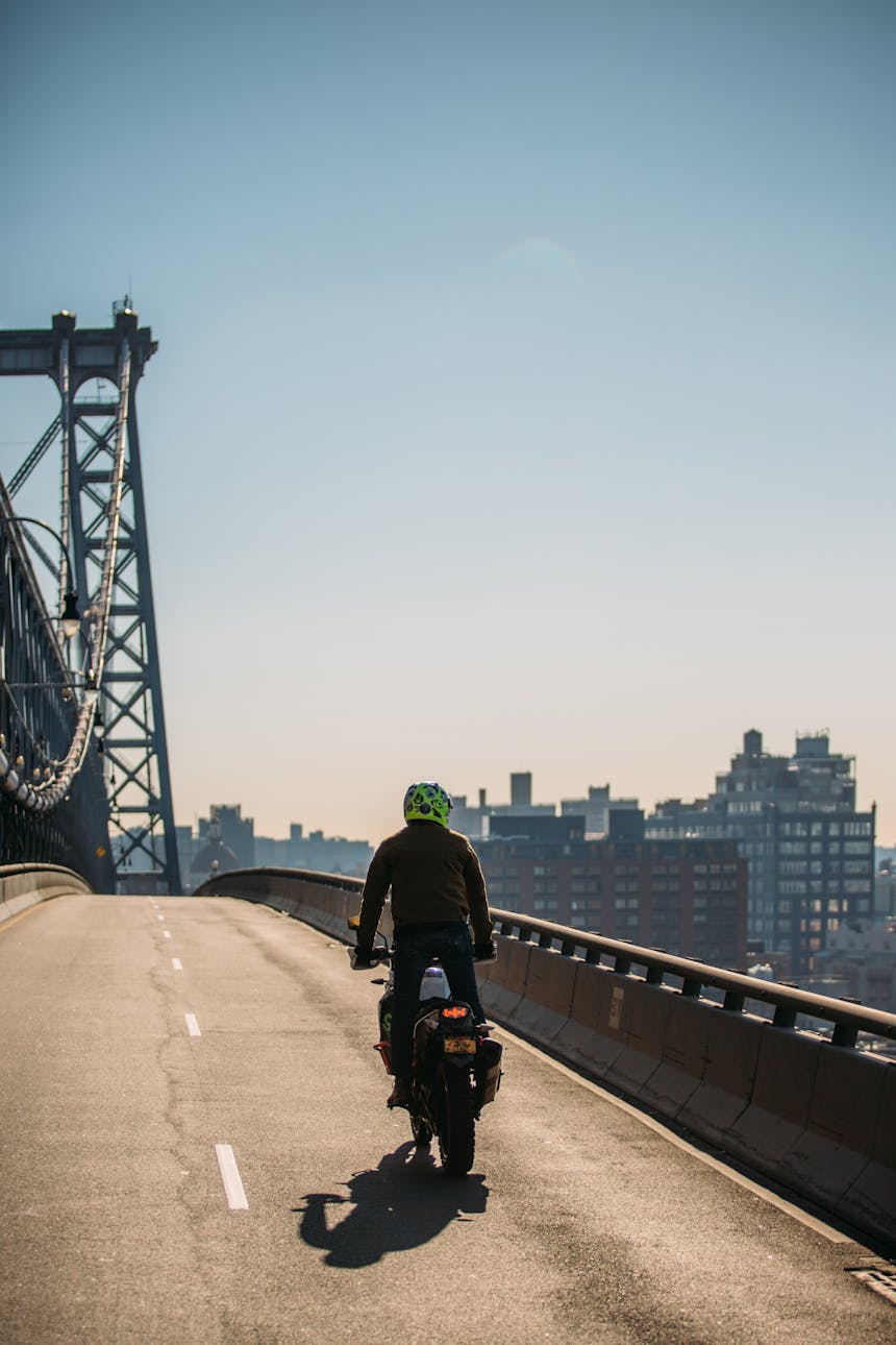 person riding motorcycle, standing up going over manhattan bridge