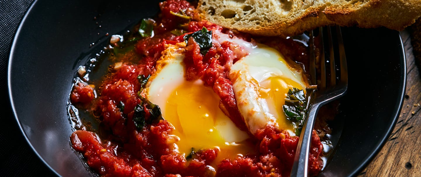 plate of eggs and red sauce with crusty bread