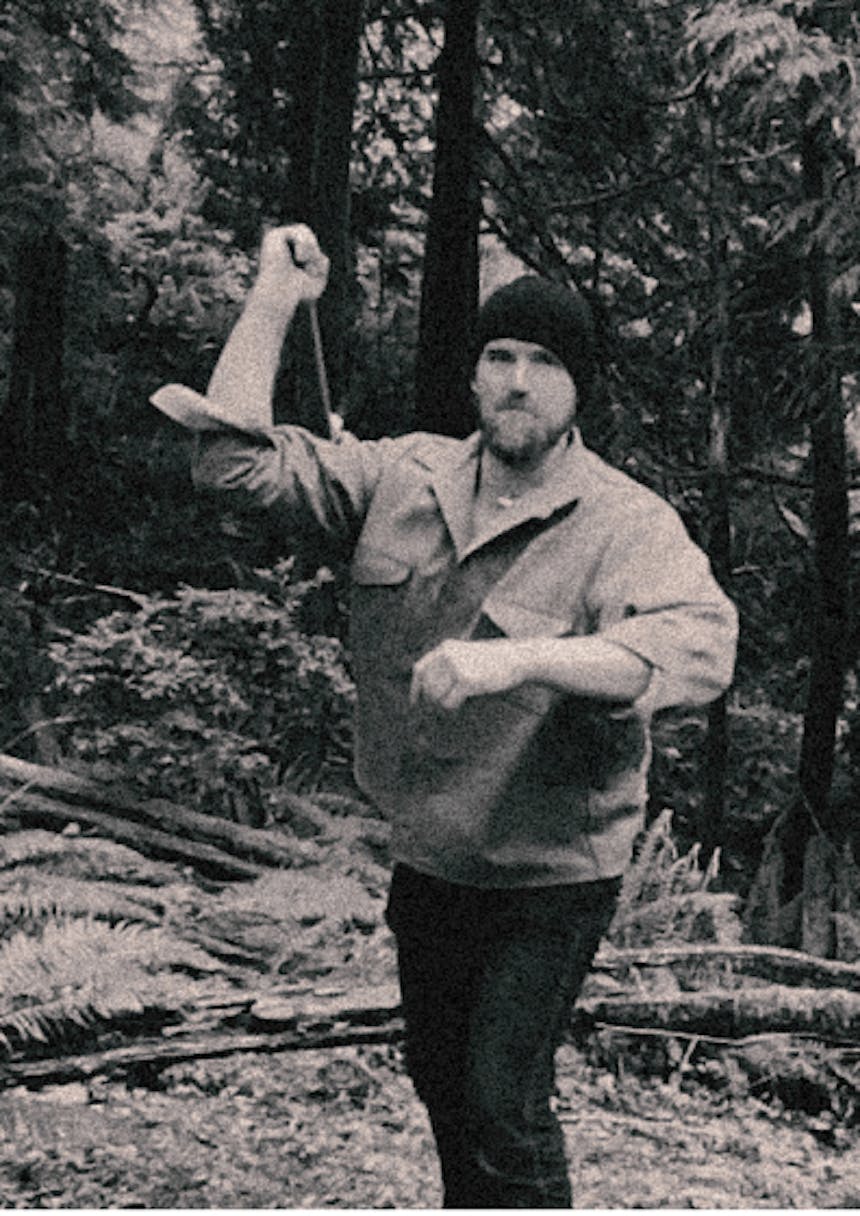 black and white image of man in black beanie preparing to throw a tomahawk