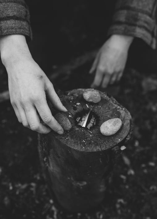 hands placing rocks on top of a rocket stove