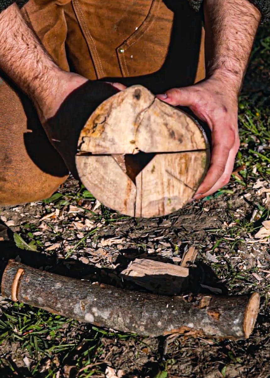 hands holding together three pieces of wood that make up a rocket stove