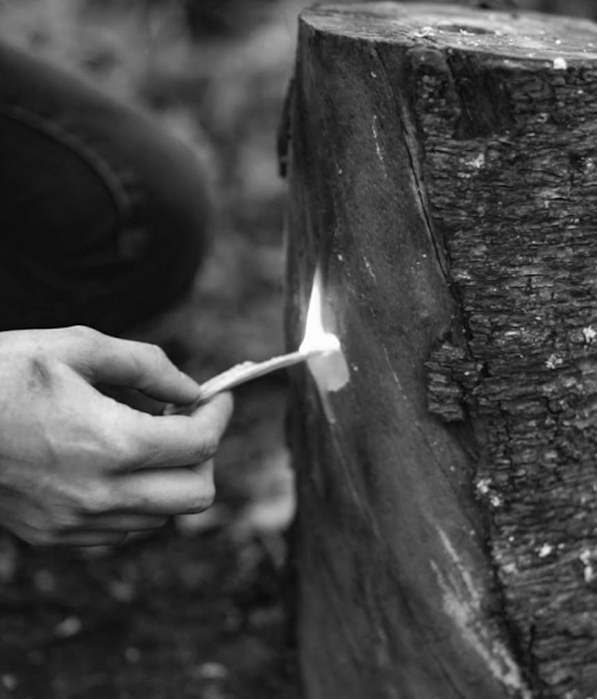 flaming kindling being put into the side hole of a rocket stove