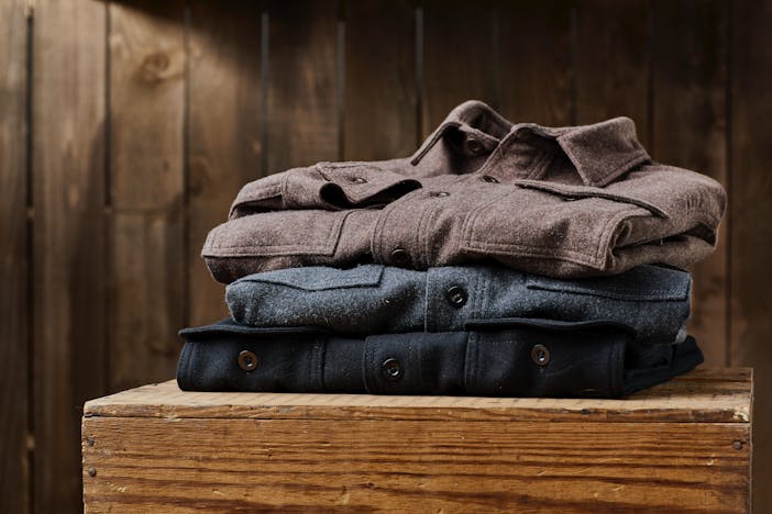 stack of wool shirts on a wooden box brown gray and navy blue